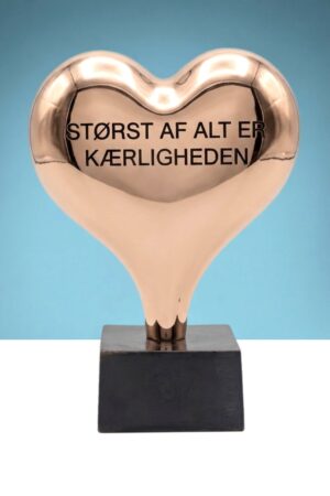 Stort blankpoleret hjerte med indgraveringen "Størst af alt er kærligheden"